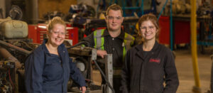 Three smiling people in a workshop