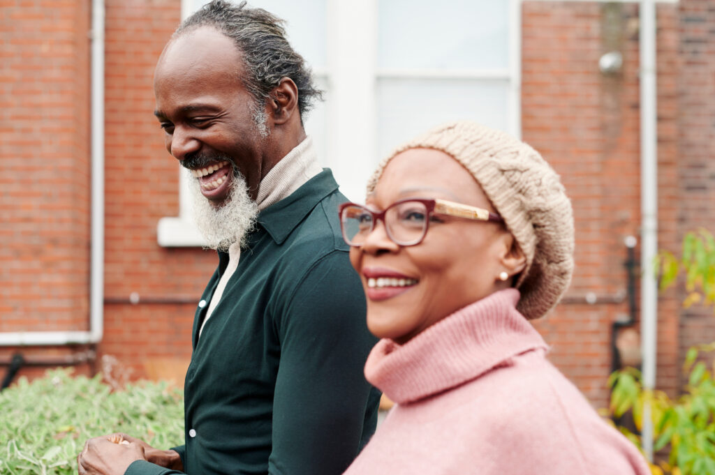 Senior African American woman laughing while going for a walk outside with her adult son